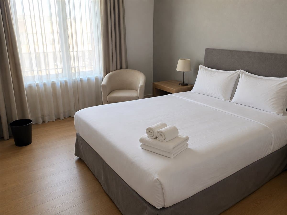 La même chambre prête : lit refait à l'hôtelière, serviettes pliées, chevet dégagé