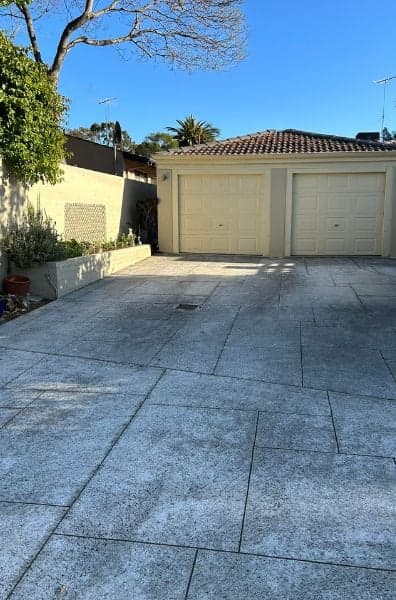 Cour dallée noircie devant un double garage