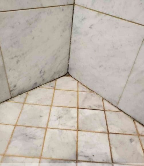 Angle de douche en marbre, joints jaunis par le calcaire
